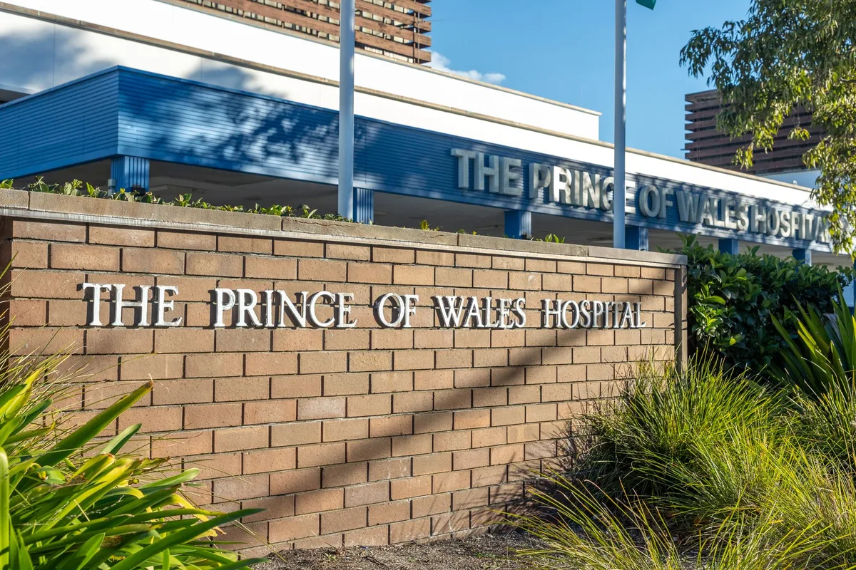 Signage at the entrance of The Prince of Wales Hospital in Sydney, Australia, surrounded by gardens on a sunny day