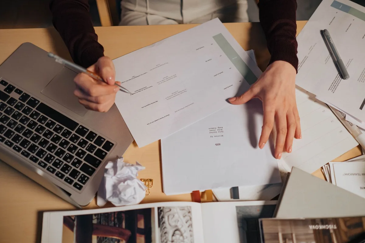 Freelancer working at a desk with a laptop and paperwork while filing contractor taxes