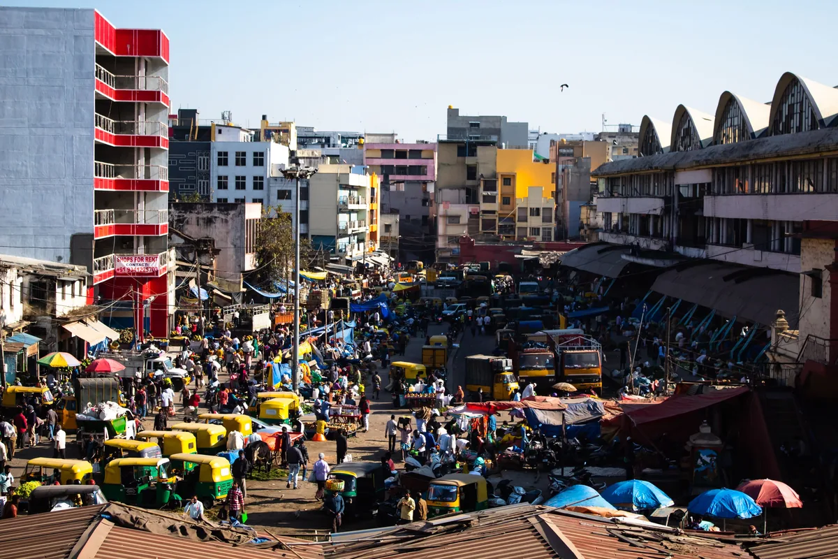 Busy Bengaluru street market with auto-rickshaws, vendors and shoppers, illustrating India take-home pay