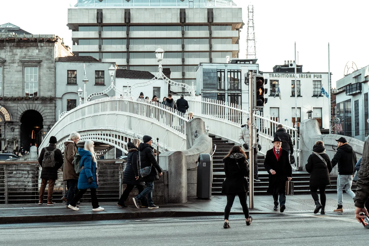Pedestrians crossing the Ha'penny Bridge over the River Liffey in Dublin, Ireland, illustrating the Irish PAYE income tax guide