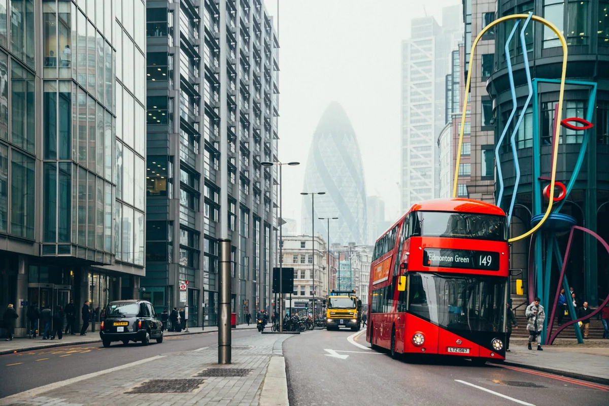 Red London double-decker bus and black cab on a City of London street, illustrating UK National Insurance
