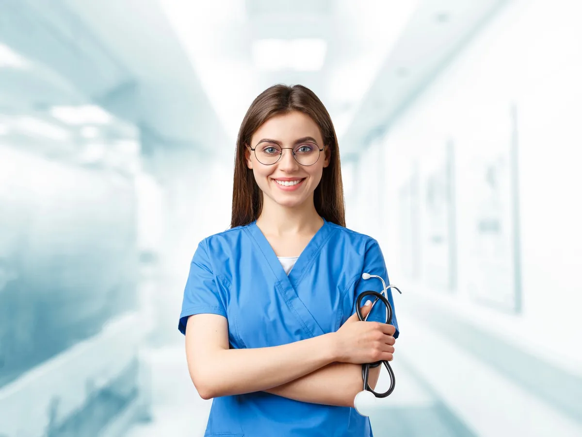 Nurse in blue scrubs holding a stethoscope in a hospital corridor, illustrating nurse pay after tax