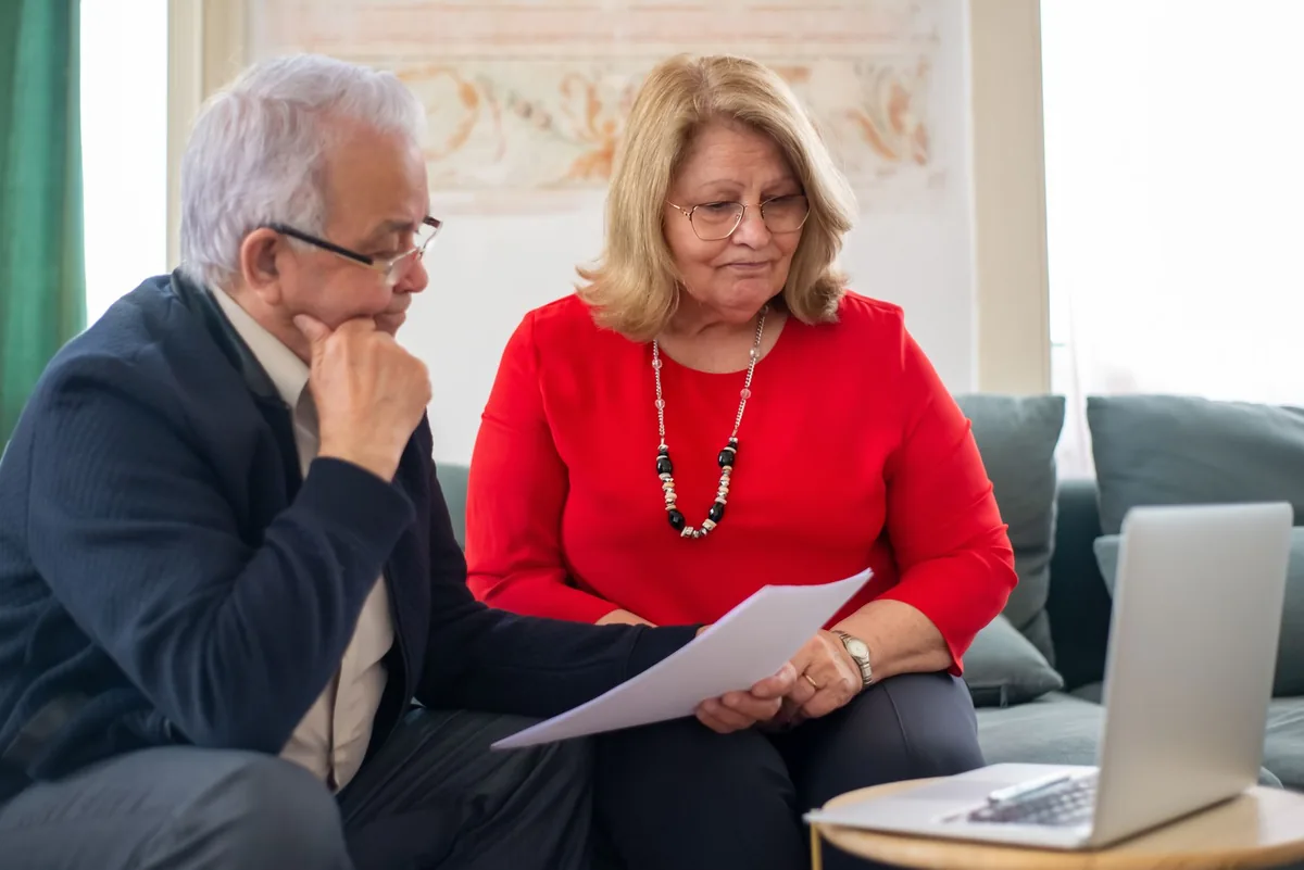 Elderly couple reviewing financial documents and paperwork at home, illustrating pension tax relief