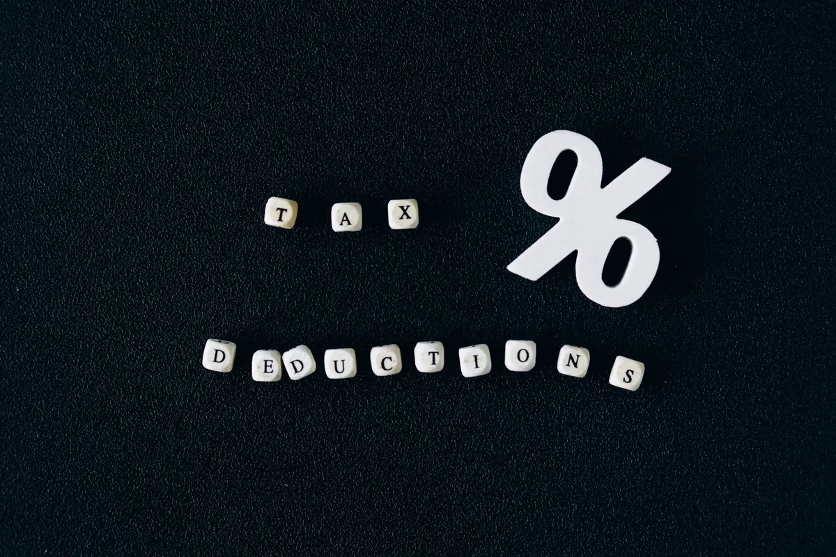 White percentage symbol beside letter blocks spelling tax deductions on a dark desk