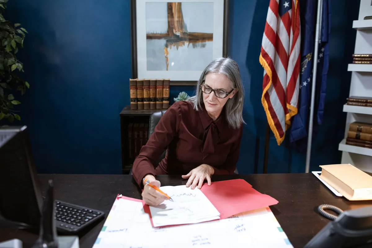 Woman reviewing US tax paperwork at a desk with an American flag in the background